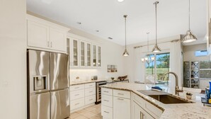 A modern kitchen with white cabinetry, stainless steel appliances, and a granite countertop. - Elegant 4-bed Home w/ Pool & Spa Near Siesta Key (Sarasota)