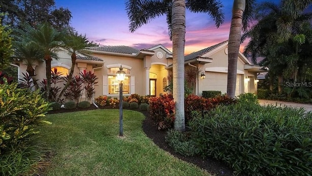 A well-maintained residential property with a landscaped garden, palm trees, and a house with a tiled roof. - Elegant 4-bed Home w/ Pool & Spa Near Siesta Key (Sarasota)