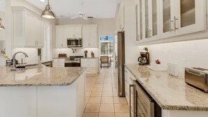 A modern kitchen with white cabinets, granite countertops, stainless steel appliances, and a central island. - Elegant 4-bed Home w/ Pool & Spa Near Siesta Key (Sarasota)
