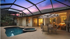 An indoor pool area with a glass ceiling, a hot tub, and a dining area with outdoor seating. - Elegant 4-bed Home w/ Pool & Spa Near Siesta Key (Sarasota)