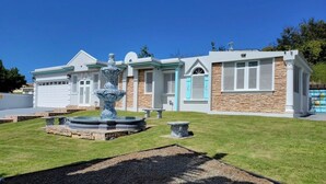 A modern house with a stone facade, a fountain, and a well-maintained lawn. - Beachy Oasis/Solar Power/Pool/Vibe 4 all ages/Big Groups 4 Family Gatherings (Manatí)