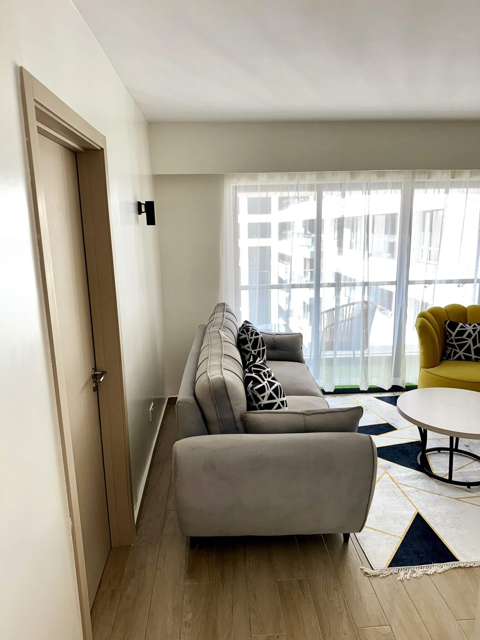 A modern living room with a grey sofa, a yellow armchair, and a round coffee table.