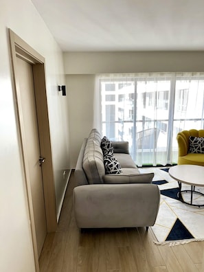En moderne stue med en grå sofa, en gul lænestol og et rundt sofabord.
