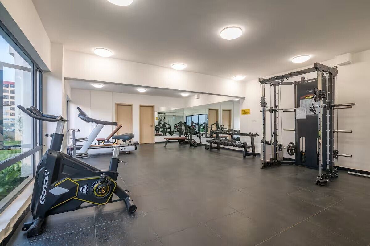 Un gimnasio con equipo de cardio, máquinas de pesas y espejos.