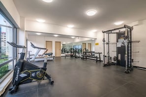 Et fitnesscenter med løbebånd, styrketræningsmaskiner og spejle.