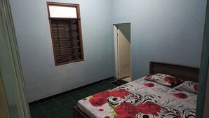 Une chambre à coucher avec un lit, une fenêtre avec des barreaux, un miroir et une armoire.