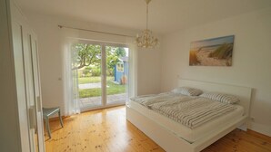Una camera da letto con un letto grande, un lampadario, una porta scorrevole in vetro che dà su un balcone e un quadro appeso al muro.