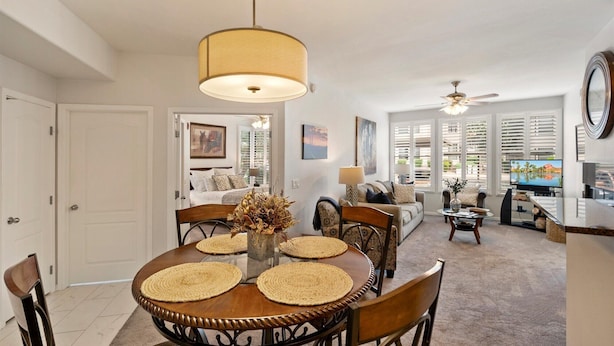 A dining area with a round table, chairs, and a hanging light fixture. - Cozy 2-bedroom condo in North Scottsdale with AC, two pools, spas, fitness room (Phoenix)