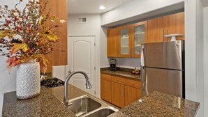 A modern kitchen with granite countertops, stainless steel appliances, and wooden cabinets. - Cozy 2-bedroom condo in North Scottsdale with AC, two pools, spas, fitness room (Phoenix)