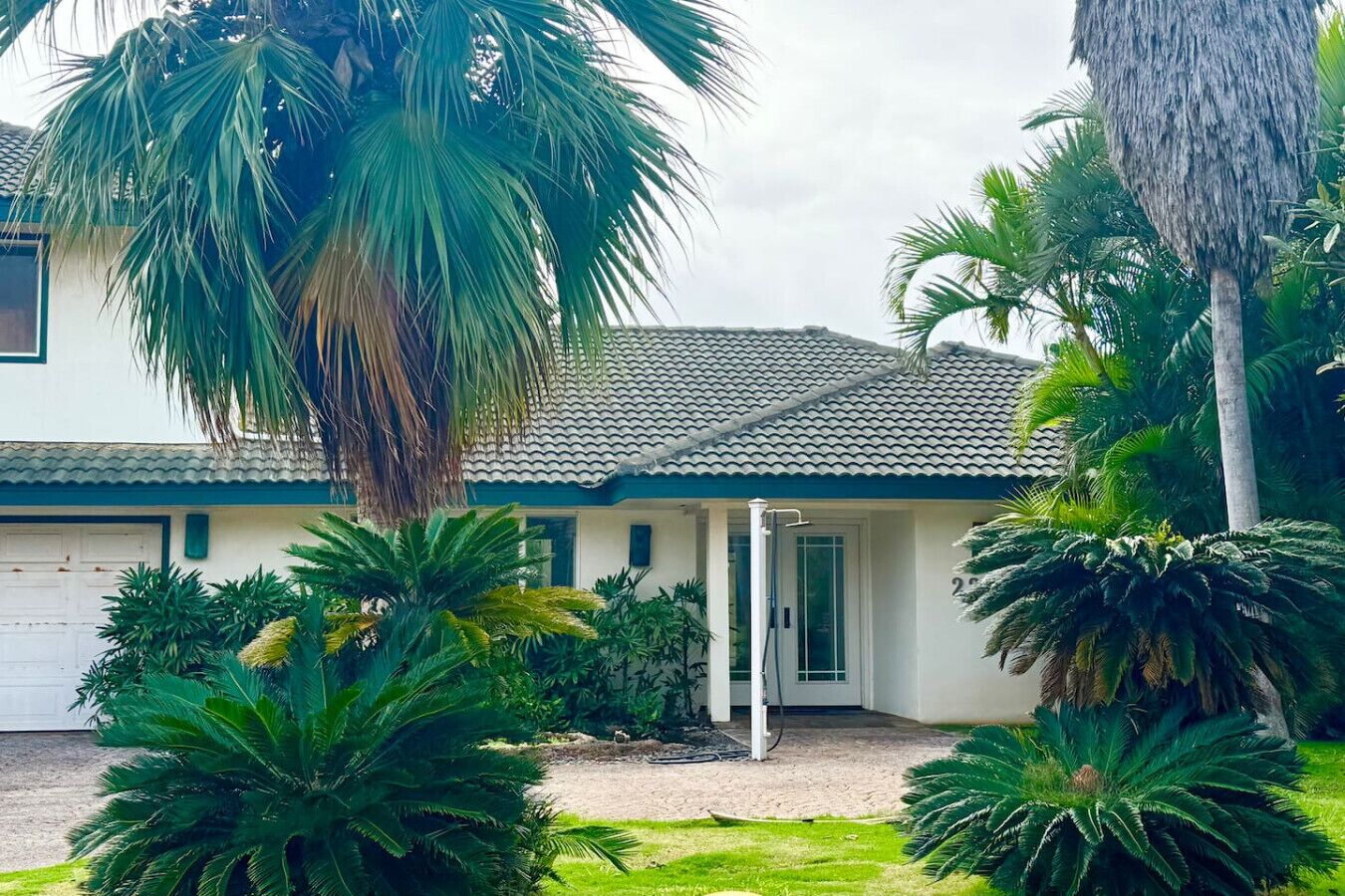 A house with a tiled roof, a garage, and a well-maintained garden with various plants.
