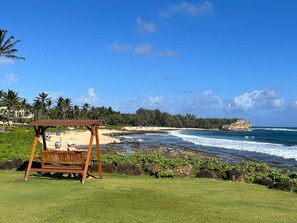 A beach view with a wooden swing, ocean waves, and a clear sky. - New! Studio Suite with Pool by Beach with AC near Hyatt (Koloa)