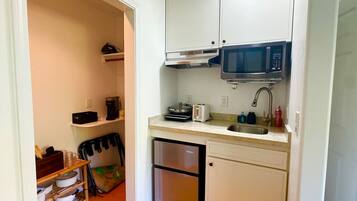 A compact kitchen with white cabinets, a microwave, a toaster, and a dishwasher.
