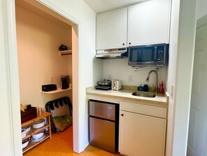 Ett kompakt kök med vita skåp, en mikrovågsugn, en brödrost och en diskmaskin.