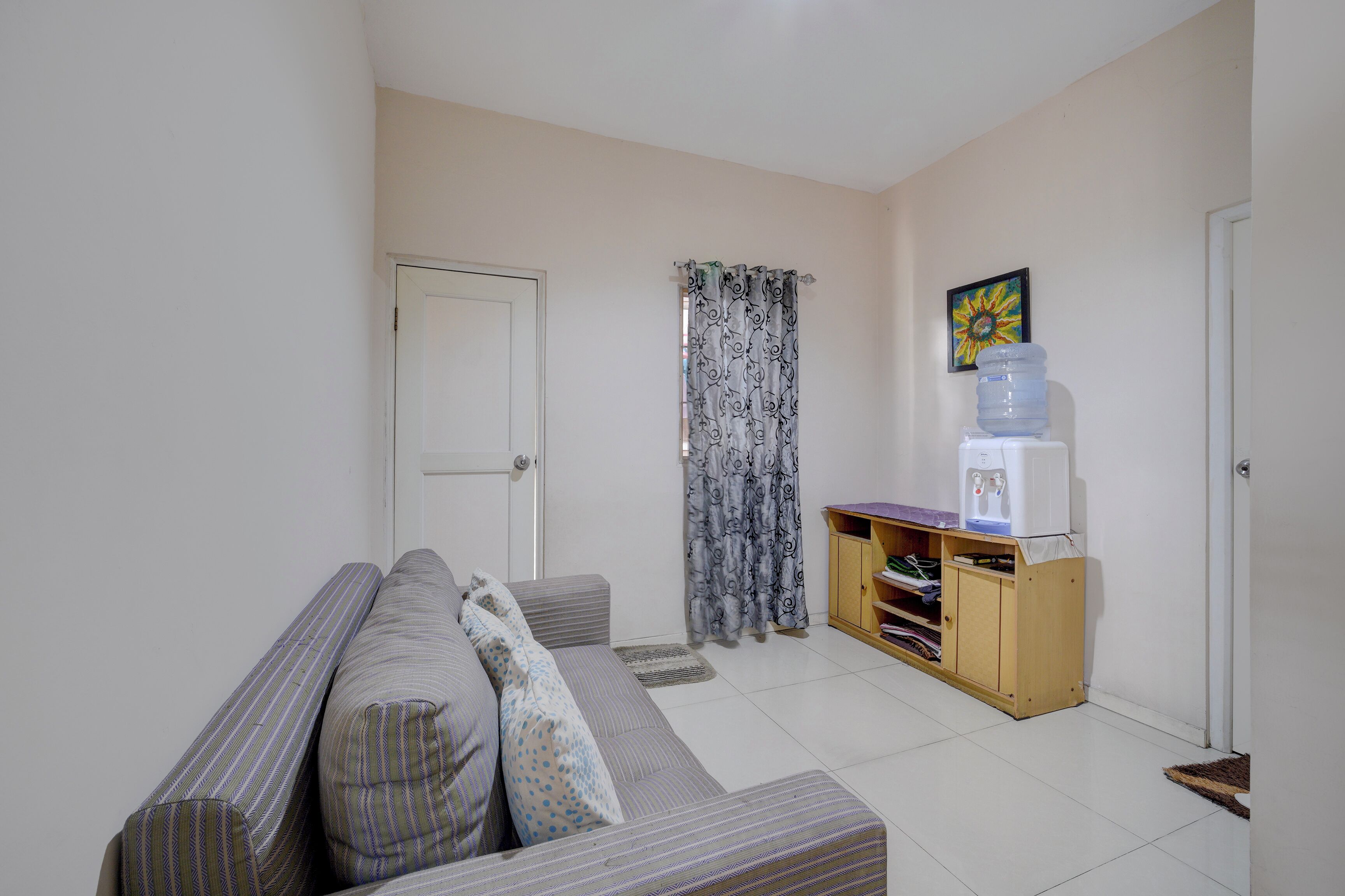 A living room with a sofa, a water dispenser, and a door.