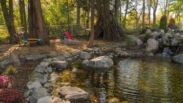 A serene outdoor setting with a small pond, rocks, and a wooden structure.