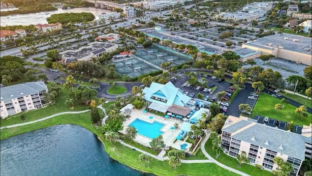 An aerial view of a resort with a swimming pool, multiple buildings, and a body of water. - The Seaside Sanctuary - Walk To The Beach and Pool (Jupiter)