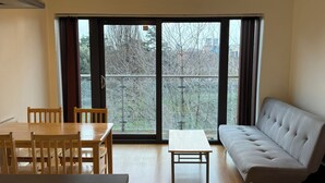 Een kamer met een eettafel, stoelen, een bank en uitzicht door grote ramen.