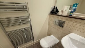 Een badkamer met een douchecabine van glas, een toilet en een wastafel.
