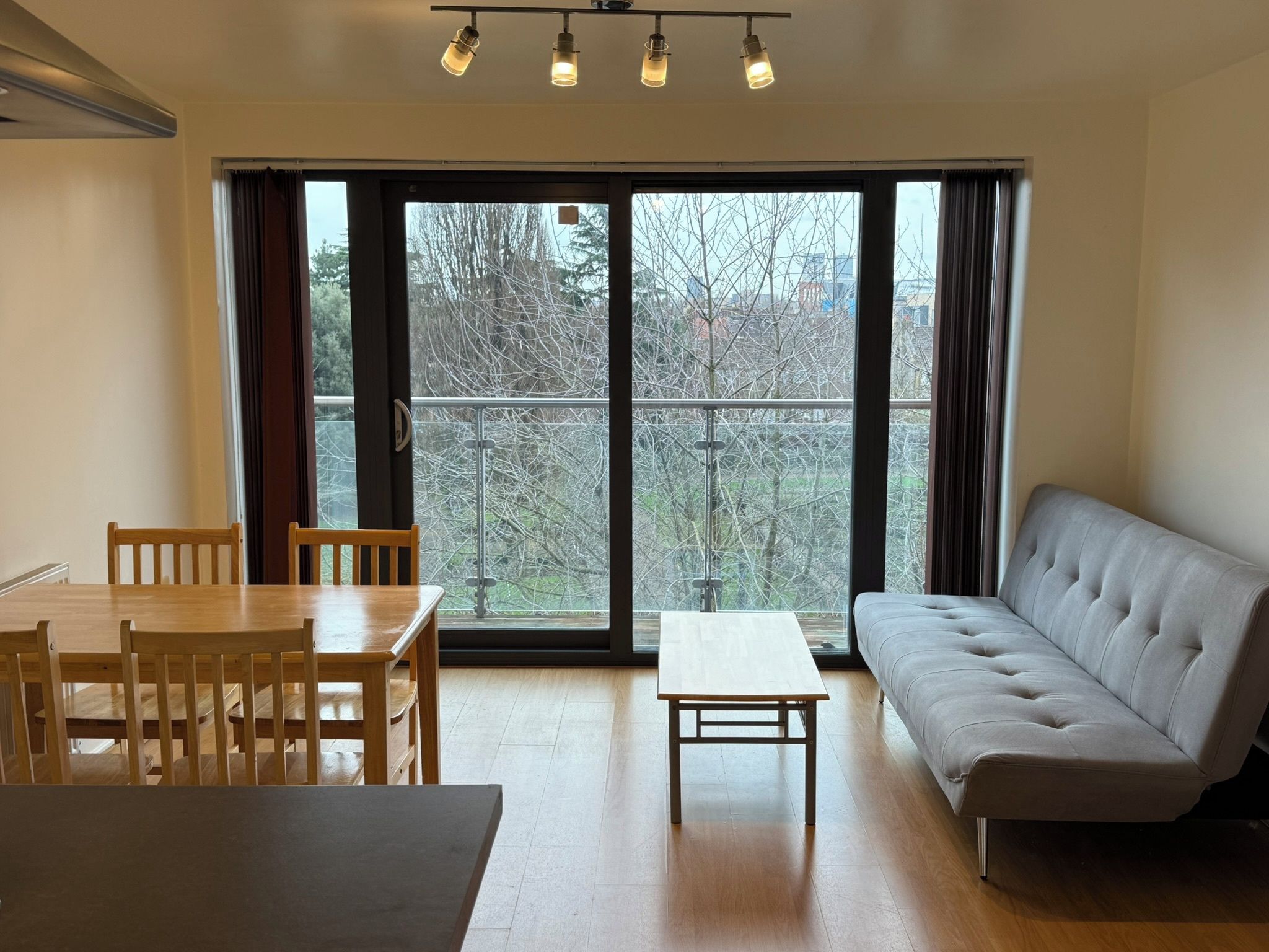 Una habitación con una mesa de comedor, sillas, un sofá y vistas a través de amplios ventanales.