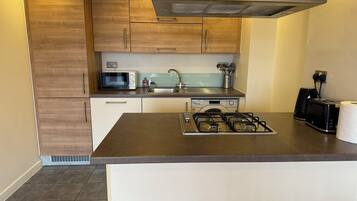 A modern kitchen with wooden cabinets, a microwave, a gas stove, and a toaster.