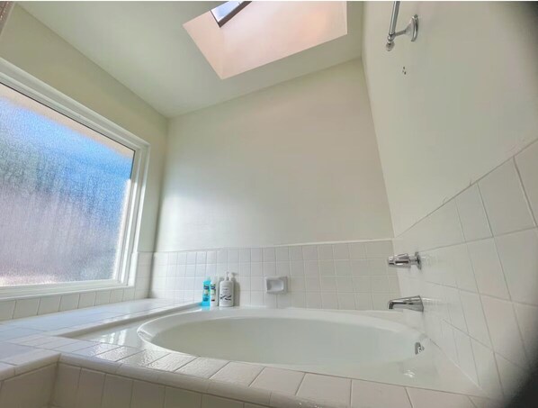 A modern bathroom with a freestanding bathtub, a skylight, and a window. - 15min to Disney - Family Fun Home! (Fullerton)