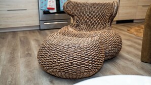 A woven pouf chair in a modern kitchen with wooden flooring and stainless steel appliances. - Little Havana Cabana – Retro Surf-Lodge Hideaway (Miami)
