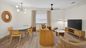 A modern living room with a dining table, sofa, TV, and decorative elements. - Little Havana Cabana – Retro Surf-Lodge Hideaway (Miami)