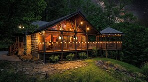 Une cabane en bois dotée d’un balcon, entourée d’arbres et bordée d’un sentier en pierre.