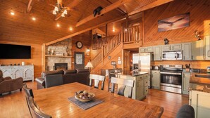A spacious living area with a fireplace, a dining table, and a kitchen with modern appliances. - Mountain Views, Family Getaway, Pet Friendly, Game Room, Sleeps 9 (Sevierville)