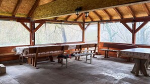 Eine rustikale Holzhütte mit hohen Decken, großen Fenstern und einem Steinfußboden.