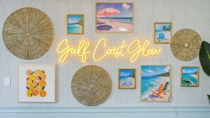 A wall decorated with beach-themed artwork and a neon sign that reads "Gulf Coast Glow". - Sleeps 12 • Game Room • Theatre • Tiki Bar • Pool (Bradenton)