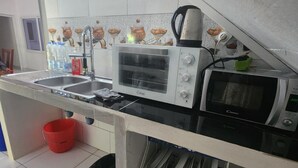 Une cuisine compacte équipée d’un four à micro-ondes, d’un grille-pain, d’un évier et d’un petit égouttoir à vaisselle.