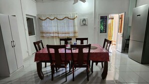 Un coin repas comprenant une table ronde, des chaises, un ventilateur de plafond et un réfrigérateur.