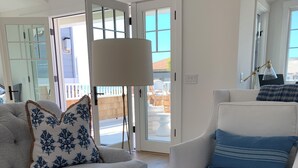En moderne stue med en grå sofa, en hvid lænestol og et glasbord med et lys.