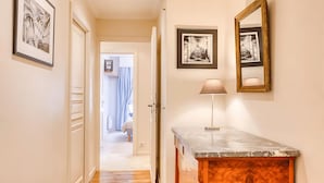 A hallway with framed artwork, a wooden cabinet, and a door leading to a room. - PARISIAN LIVING IN LE MARAIS: SPACIOUS FAMILY APARTMENT WITH GARDEN VIEW - 3 BED (Paris)