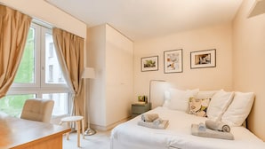 A bedroom with a bed, a desk, a chair, a nightstand, and a window with curtains. - PARISIAN LIVING IN LE MARAIS: SPACIOUS FAMILY APARTMENT WITH GARDEN VIEW - 3 BED (Paris)