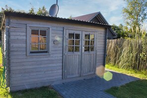 A wooden shed with two windows and a door, a satellite dish, and a brick pathway leading to it. - Vacation home Aurora (Twist)