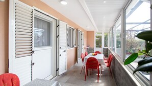 A corridor with a table and chairs, a window, and a door with shutters. - Guest House 4M Gregović - Three bedroom apartment (Petrovac na Moru)