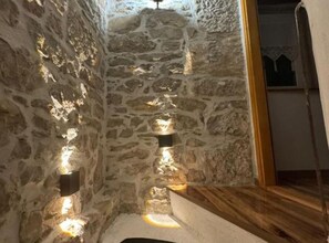 A narrow stone-walled corridor with built-in lighting fixtures and a wooden bench. - Elegant Apartment Judita - Two Bedroom Apartment (Sveti Martin pri Buzetu)
