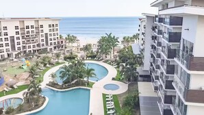 Un resort con una piscina grande, palme e vista sull'oceano.