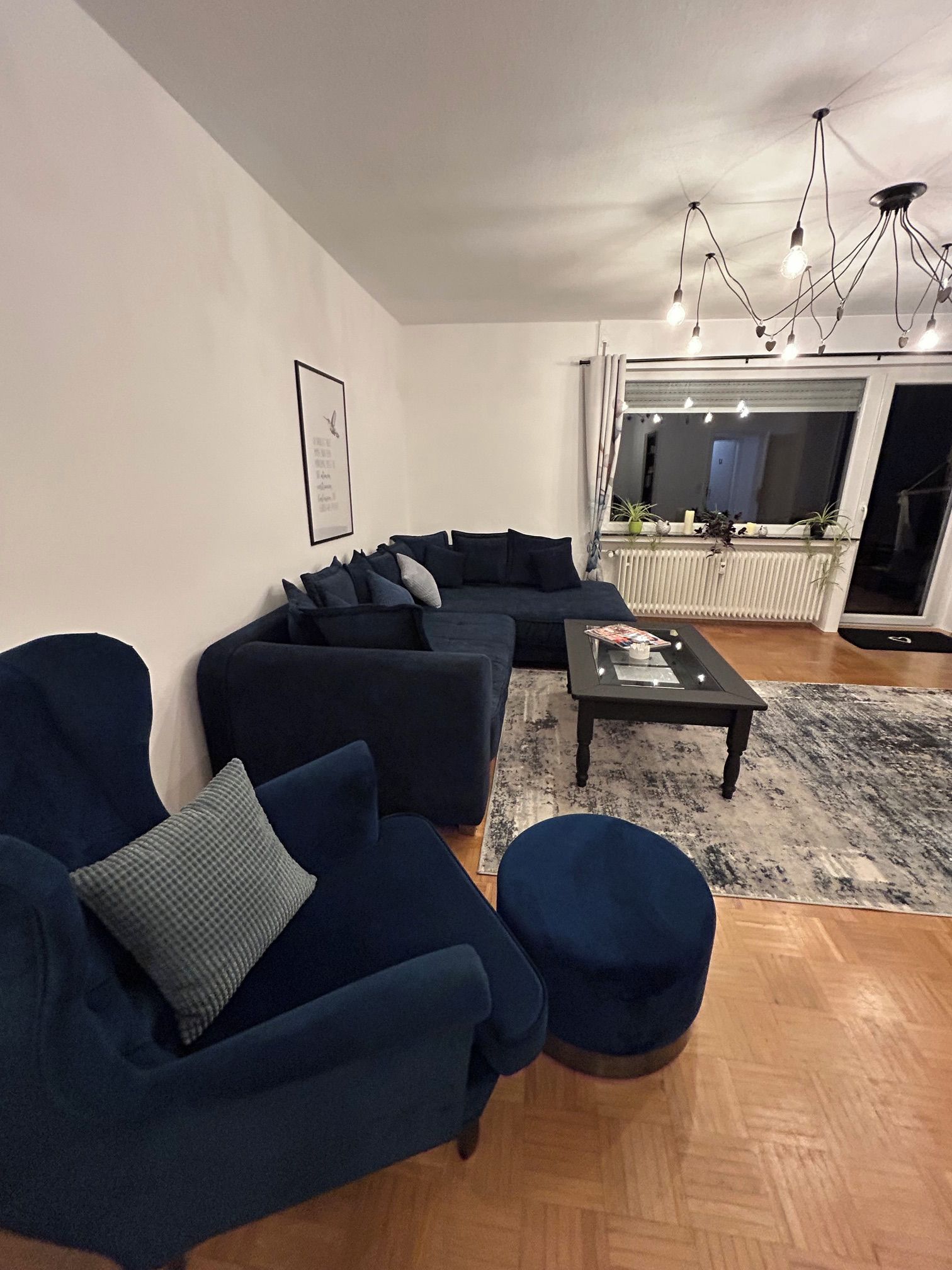A modern living room with a sectional sofa, a round ottoman, a coffee table, and a large mirror.