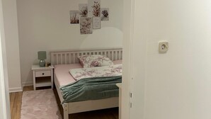 Une chambre à coucher comprenant un lit, une table de chevet, une étagère murale décorative et un plancher en bois.