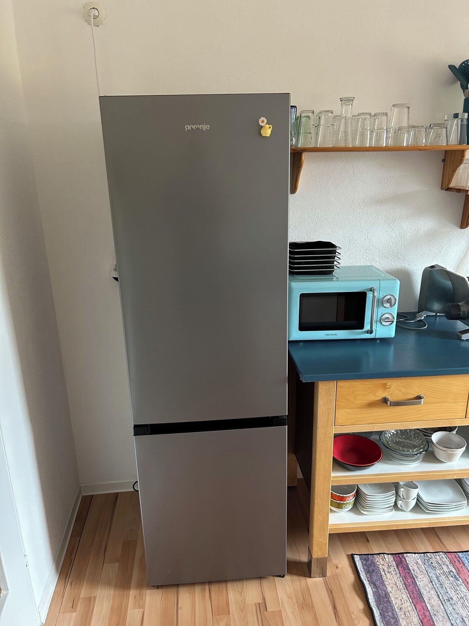 A compact kitchen with a built-in refrigerator, a microwave, and a wooden countertop.