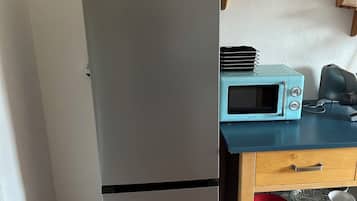A compact kitchen with a built-in refrigerator, a microwave, and a wooden countertop.