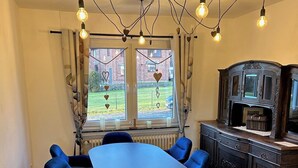 Un coin repas avec une grande table ovale entourée de six chaises bleues, un buffet en bois foncé et un lustre doté de plusieurs ampoules.