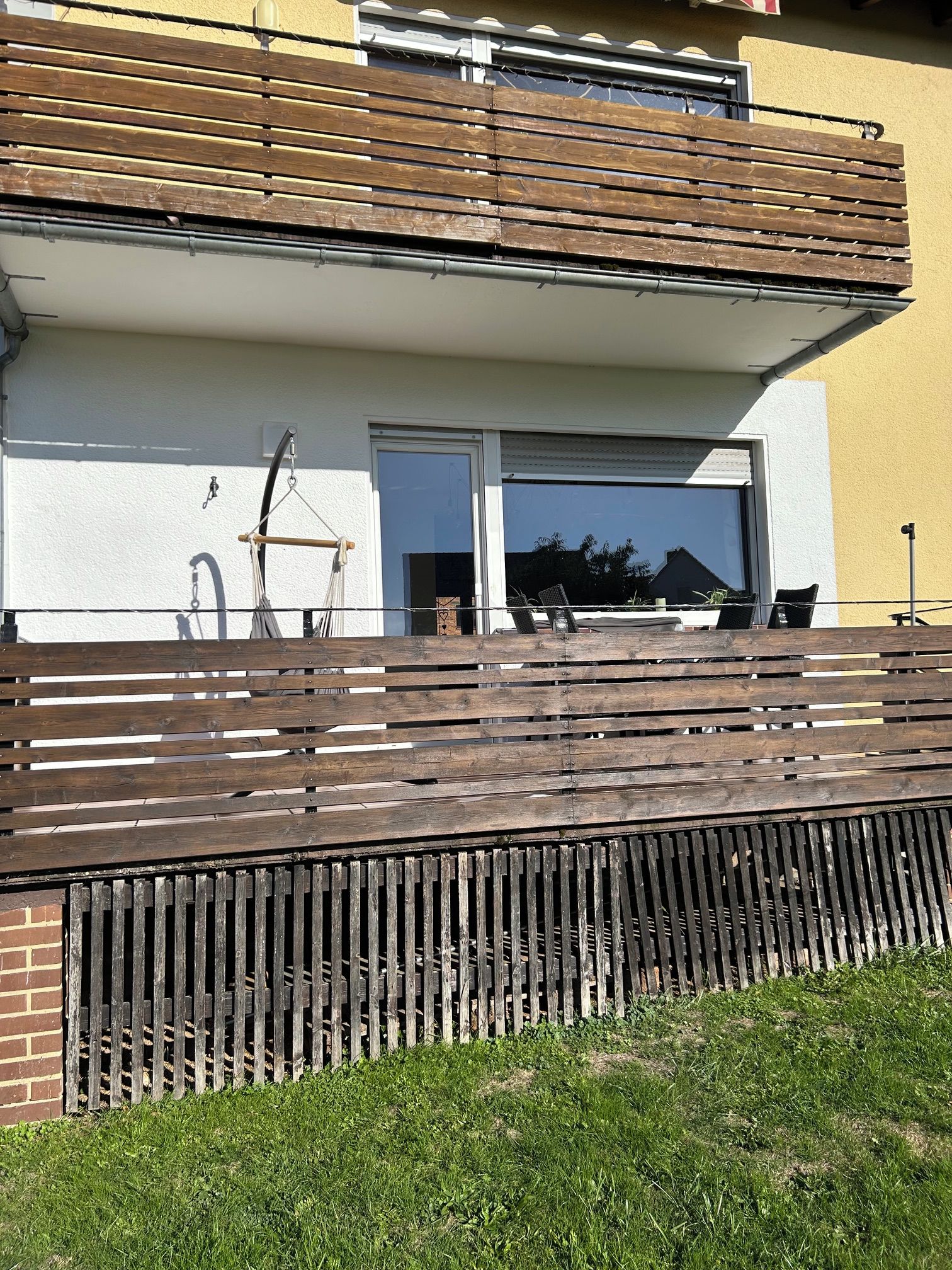 En moderne bygning med et fladt tag, en balkon med trægelændere og en murstensvæg.