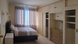 Een slaapkamer met een bed, een kledingkast en een klein nachtkastje.