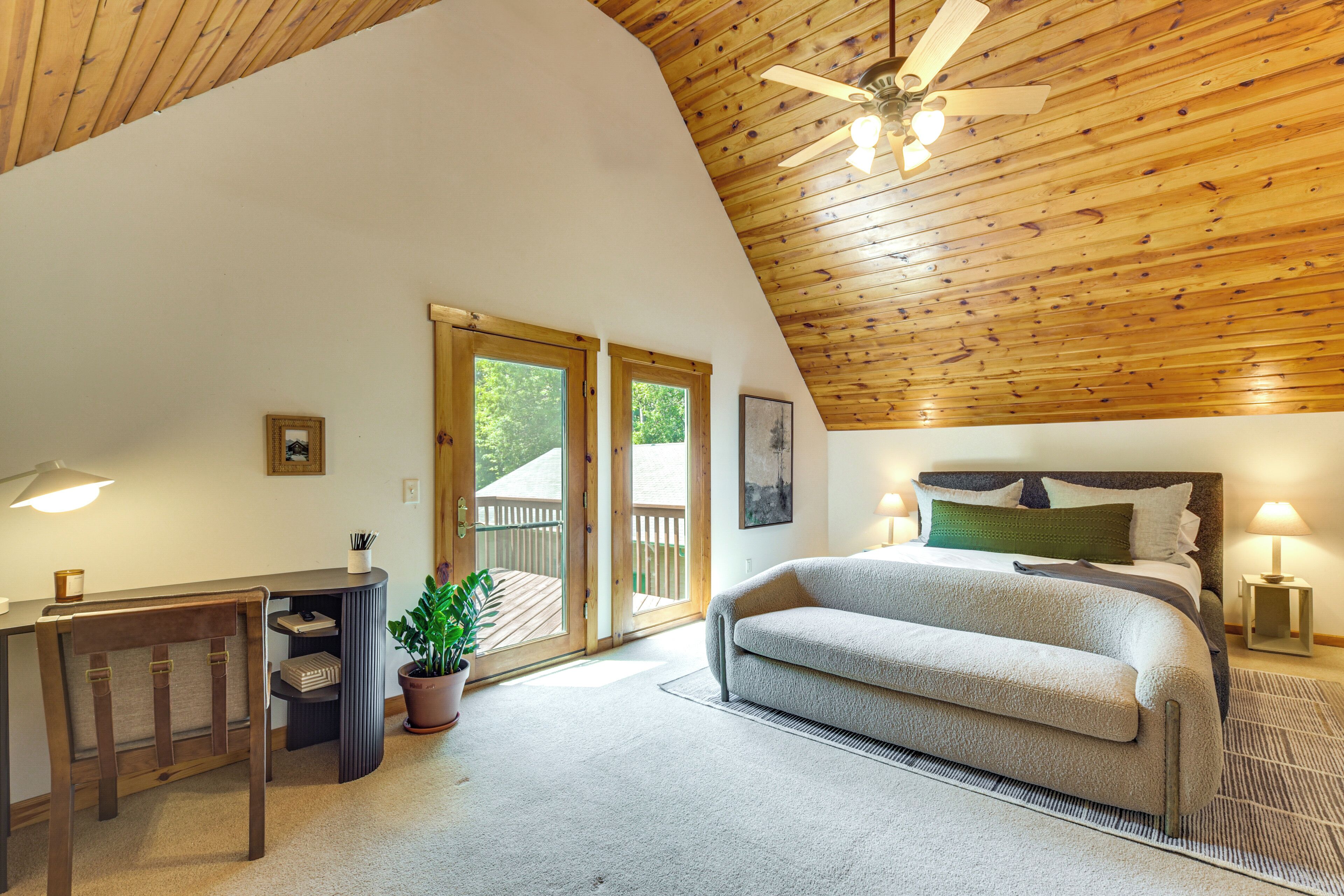 Ein Schlafzimmer mit Holzboden, einem Bett, einem Schreibtisch mit Stuhl und einer Topfpflanze.