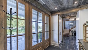 Un interior de madera con amplios ventanales, una escalera de piedra y una araña.