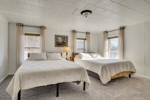 Habitación de hotel con dos camas, una lámpara en el techo, un cuadro en la pared y una ventana con cortinas.